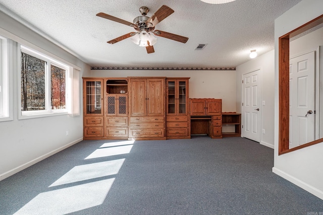 interior space featuring visible vents, a ceiling fan, carpet flooring, a textured ceiling, and baseboards