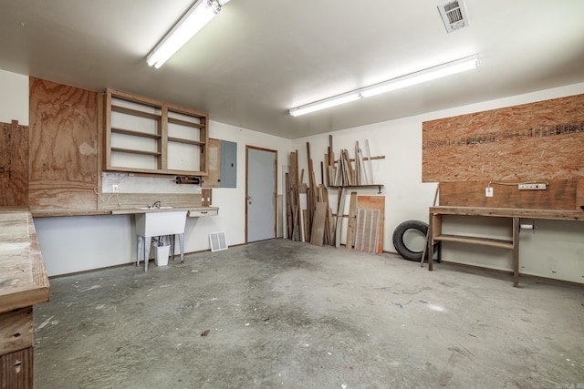 garage with electric panel, visible vents, and a workshop area