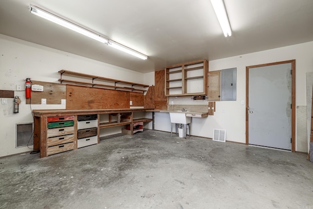 garage featuring electric panel, visible vents, and a workshop area