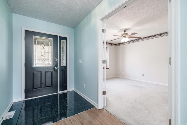 foyer entrance with a ceiling fan, a textured ceiling, baseboards, and wood finished floors