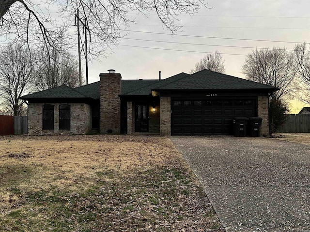 view of front of home featuring aphalt driveway, roof with shingles, a chimney, an attached garage, and fence