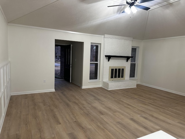 unfurnished living room featuring a ceiling fan, a fireplace, ornamental molding, and wood finished floors