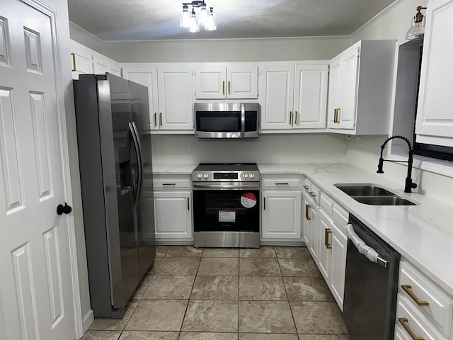 kitchen featuring white cabinets, light stone countertops, stainless steel appliances, a textured ceiling, and a sink