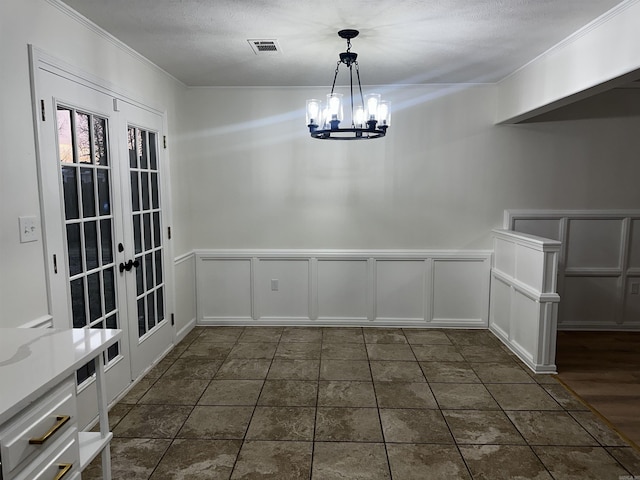 unfurnished dining area featuring french doors, a notable chandelier, visible vents, ornamental molding, and a textured ceiling