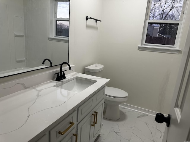 bathroom with marble finish floor, vanity, toilet, and baseboards