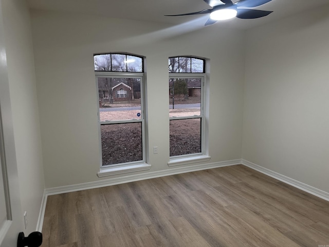 empty room with a ceiling fan, baseboards, and wood finished floors