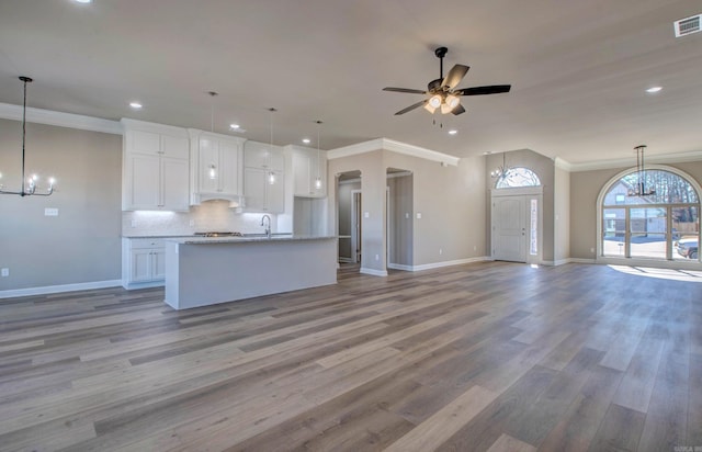 kitchen featuring white cabinets, tasteful backsplash, ornamental molding, and open floor plan