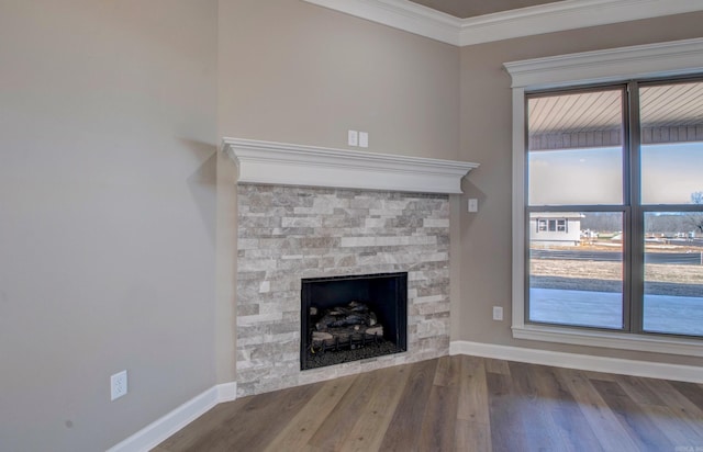 unfurnished living room with ornamental molding, a fireplace, baseboards, and wood finished floors