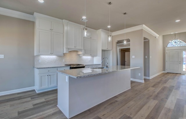 kitchen with tasteful backsplash, stove, a sink, and white cabinetry