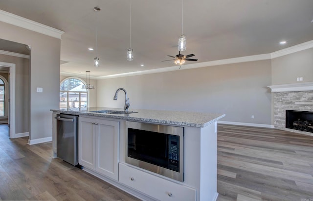 kitchen featuring a fireplace, light wood-style flooring, appliances with stainless steel finishes, open floor plan, and a sink