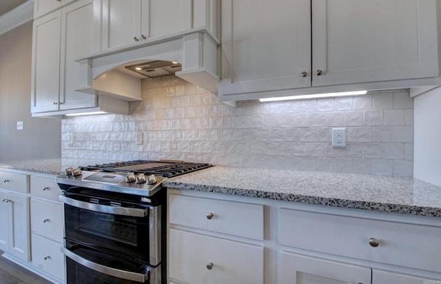 kitchen with range with two ovens, white cabinetry, decorative backsplash, and light stone countertops