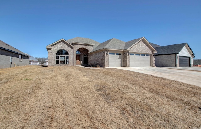 view of front of property with brick siding, roof with shingles, concrete driveway, a garage, and a front lawn