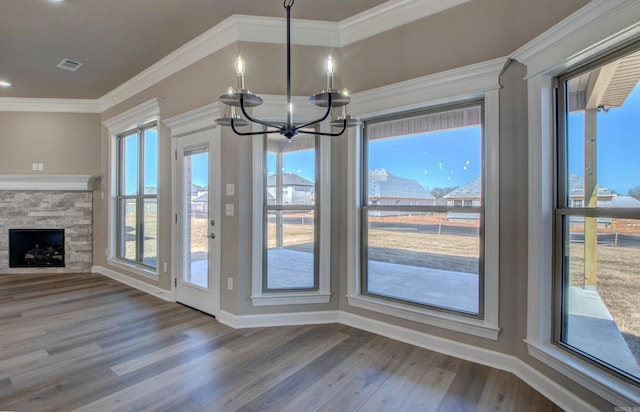 unfurnished dining area featuring ornamental molding, a fireplace, and wood finished floors