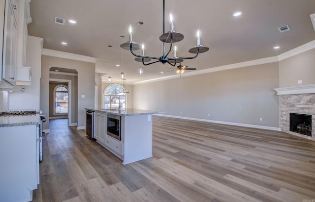 kitchen featuring stainless steel appliances, a fireplace, a sink, visible vents, and open floor plan