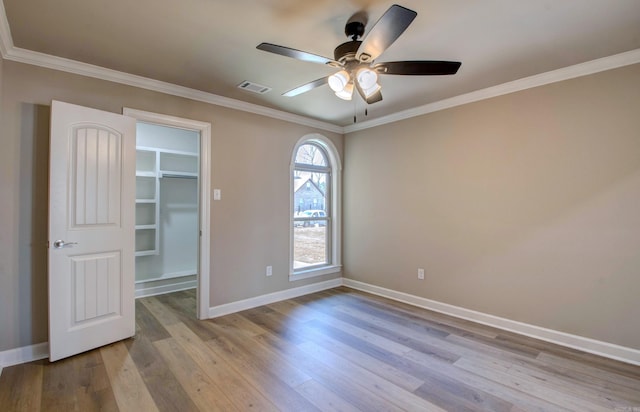 spare room featuring ornamental molding, wood finished floors, a ceiling fan, and baseboards