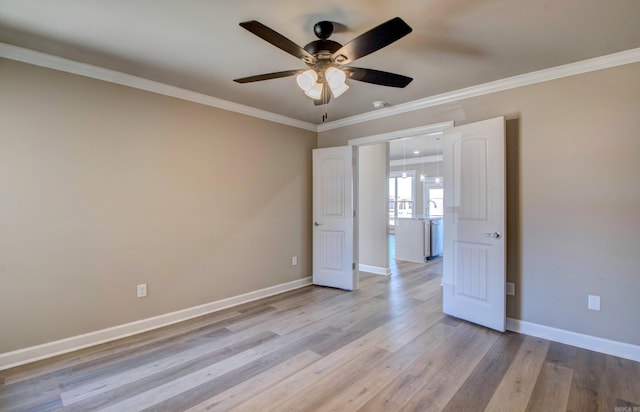 empty room with ornamental molding, light wood-type flooring, and baseboards