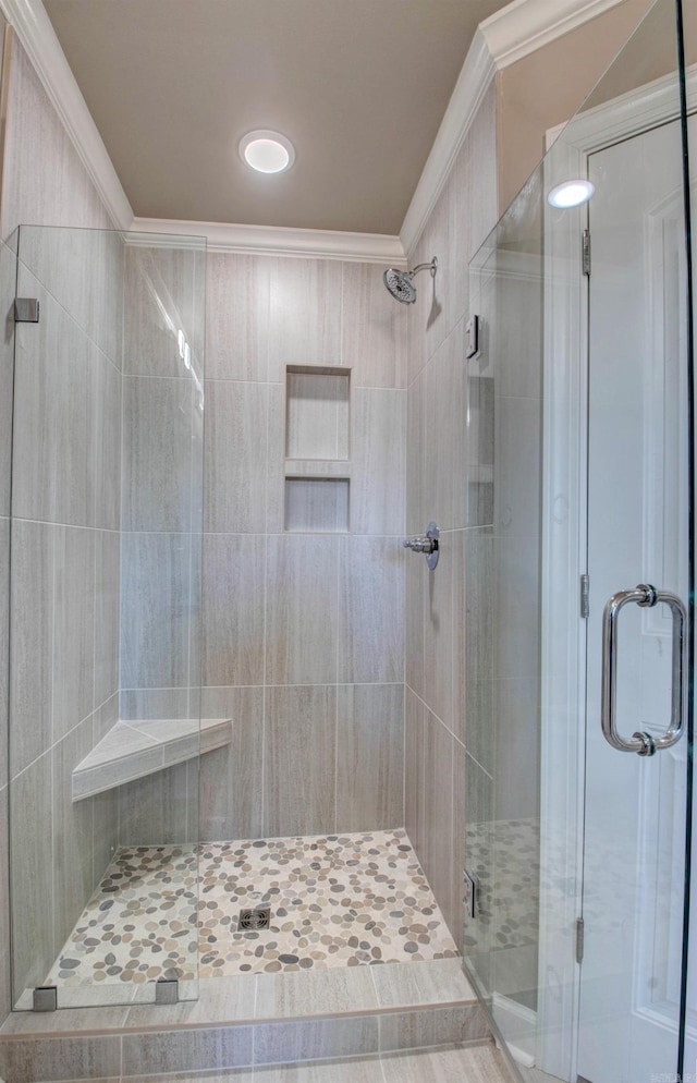 full bath with ornamental molding and a shower stall