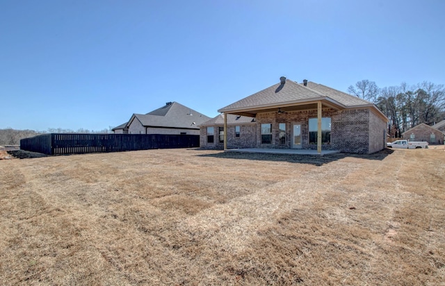 back of house with brick siding, fence, and a patio