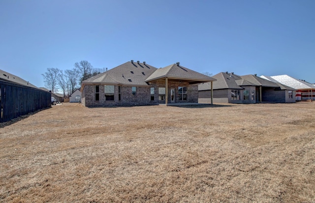 back of house featuring a lawn and brick siding