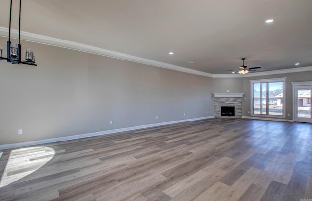 unfurnished living room featuring ceiling fan, baseboards, crown molding, and wood finished floors