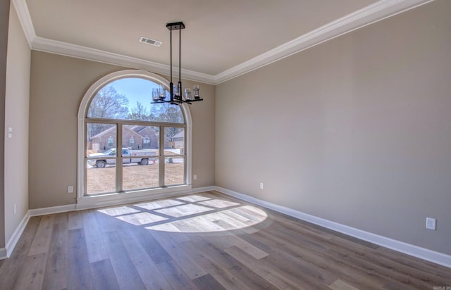 unfurnished dining area with a notable chandelier, visible vents, crown molding, and wood finished floors