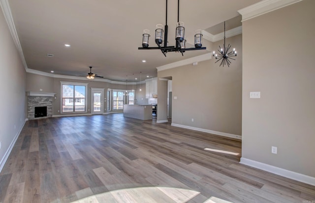 unfurnished living room featuring crown molding, a fireplace, baseboards, and wood finished floors