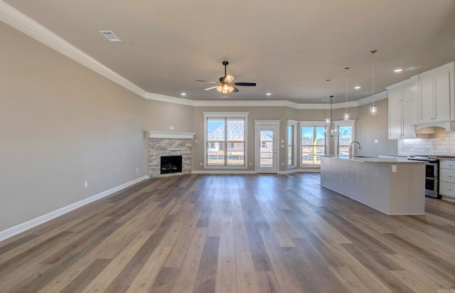 kitchen with tasteful backsplash, an island with sink, open floor plan, wood finished floors, and double oven range