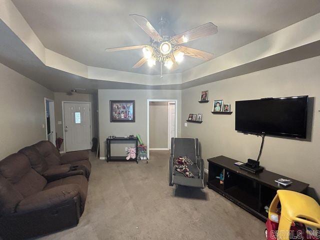 living area with carpet floors, a tray ceiling, and a ceiling fan