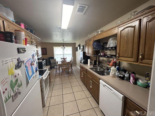 kitchen featuring light tile patterned floors, light countertops, visible vents, a sink, and white appliances