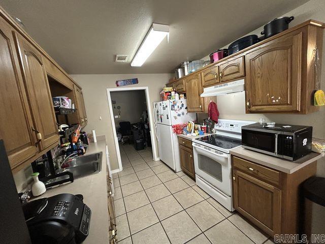 kitchen with white appliances, light countertops, a sink, and under cabinet range hood