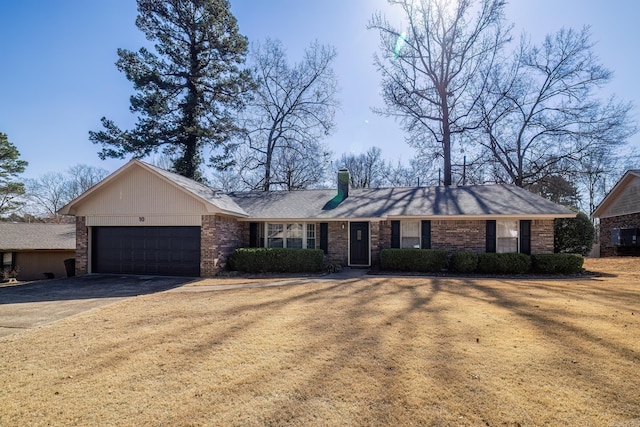 ranch-style home with brick siding, a chimney, an attached garage, a front yard, and driveway