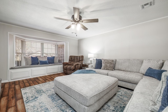 living room featuring crown molding, visible vents, ceiling fan, and wood finished floors