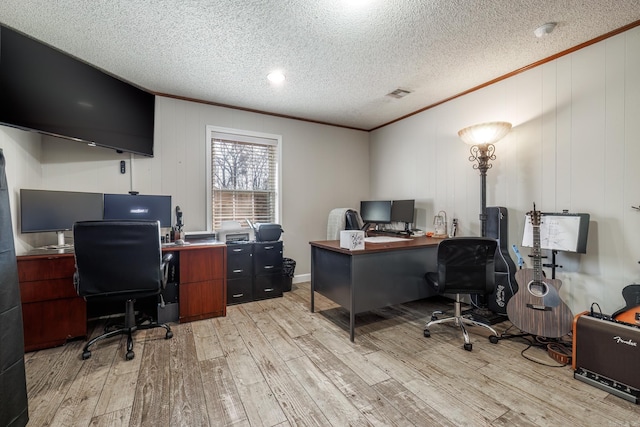 home office with light wood finished floors, visible vents, ornamental molding, and a textured ceiling