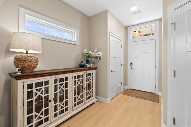 foyer entrance with wood finished floors, visible vents, and baseboards