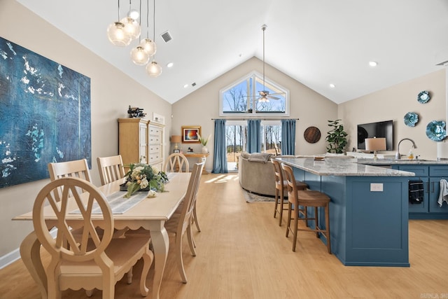 dining area with light wood-type flooring, high vaulted ceiling, ceiling fan, and visible vents