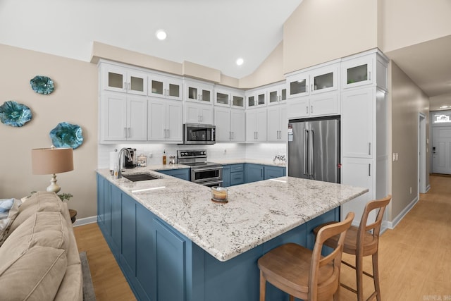 kitchen featuring stainless steel appliances, a breakfast bar, a peninsula, a sink, and white cabinets