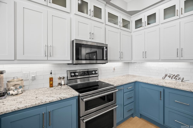 kitchen with blue cabinetry, appliances with stainless steel finishes, and backsplash