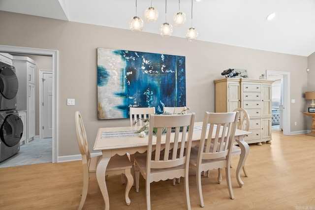 dining room with light wood-style floors, stacked washer and clothes dryer, and baseboards