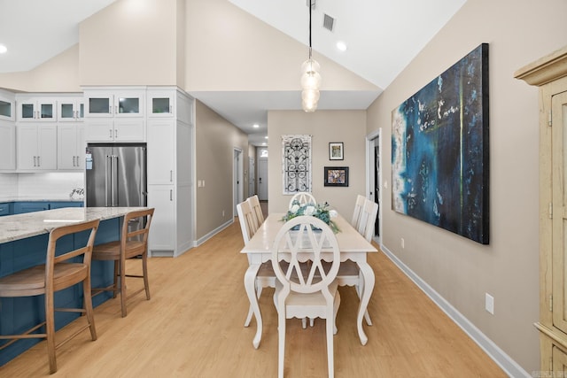 dining area with baseboards, high vaulted ceiling, visible vents, and light wood-style floors