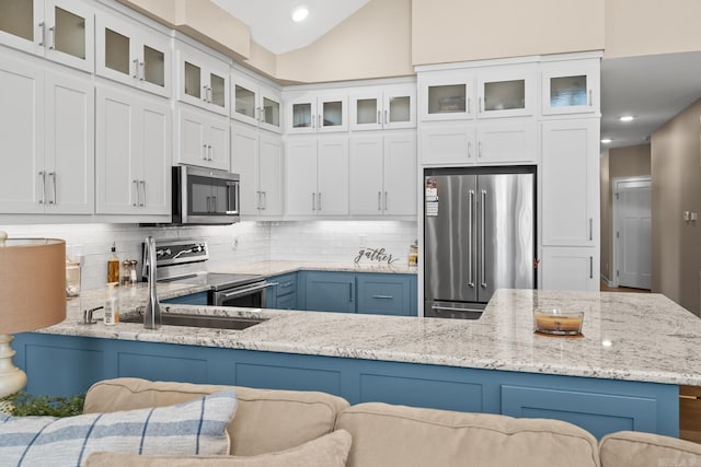 kitchen featuring light stone counters, white cabinetry, appliances with stainless steel finishes, tasteful backsplash, and glass insert cabinets