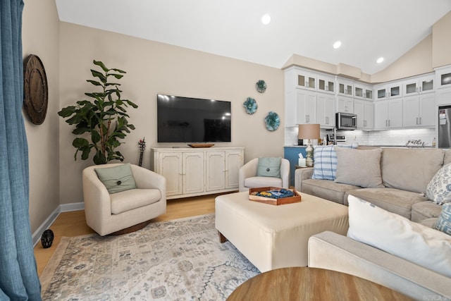 living area with light wood-type flooring, lofted ceiling, baseboards, and recessed lighting