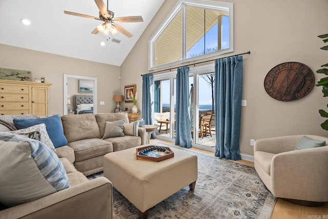 living room with visible vents, baseboards, a ceiling fan, wood finished floors, and high vaulted ceiling