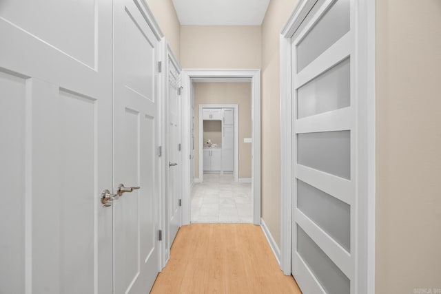 corridor featuring light wood-type flooring and baseboards