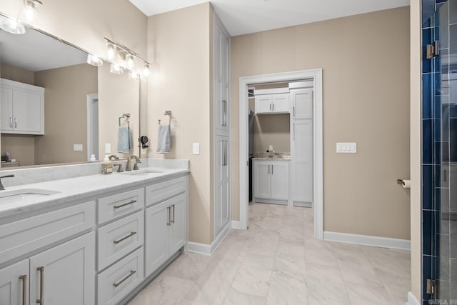 bathroom featuring double vanity, baseboards, and a sink