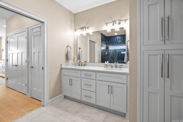 full bathroom with a sink, baseboards, and double vanity