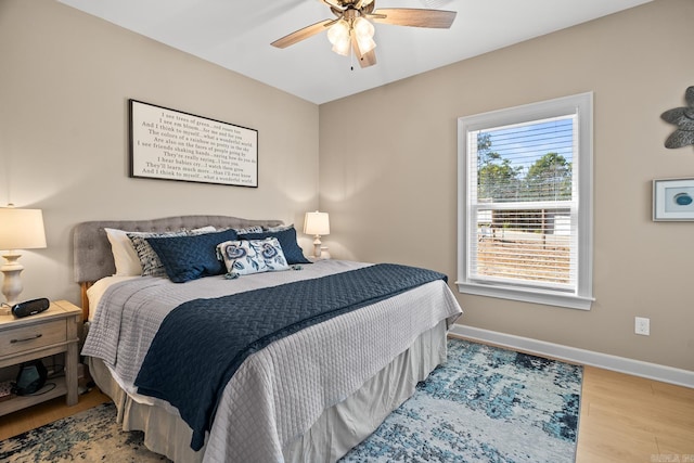 bedroom featuring ceiling fan, baseboards, and wood finished floors