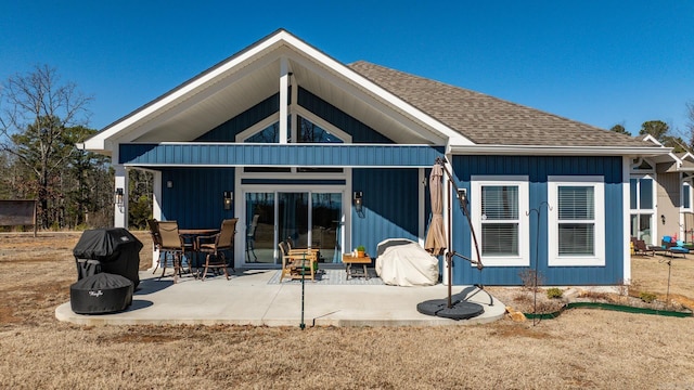 back of property featuring roof with shingles, a patio, and a fire pit