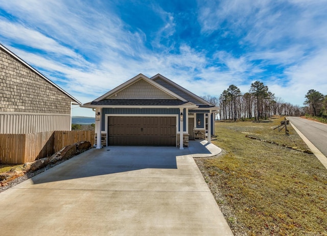 view of front facade with a garage, concrete driveway, stone siding, and fence