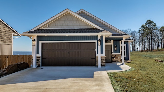 view of front of property with a shingled roof, concrete driveway, stone siding, an attached garage, and fence