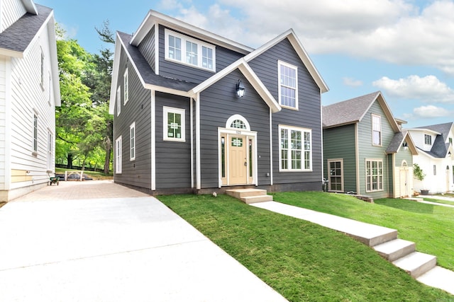 view of front of house featuring a shingled roof and a front lawn